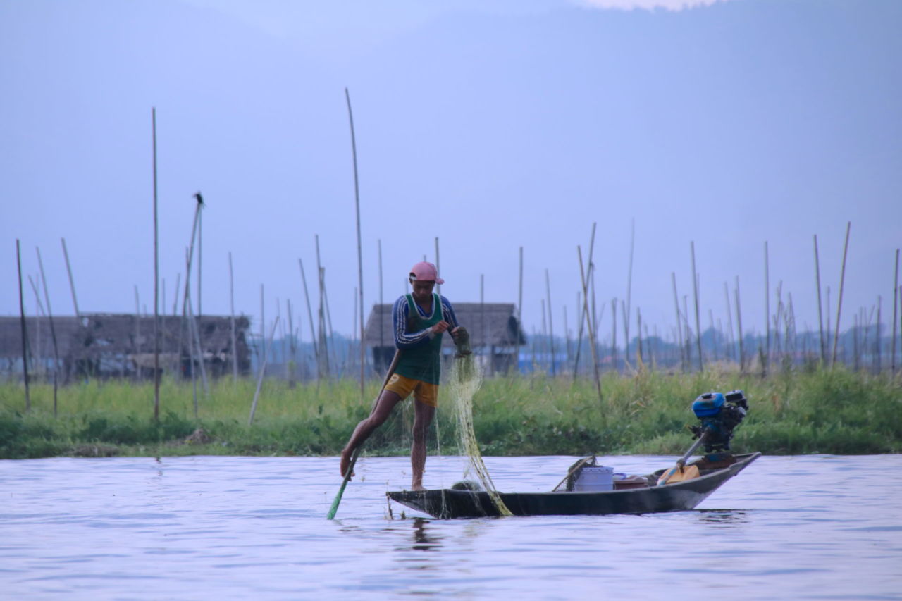 Ein Fischer auf dem Inle-See Ein Fischer mit einem Netz auf einem Boot auf dem Inlesee