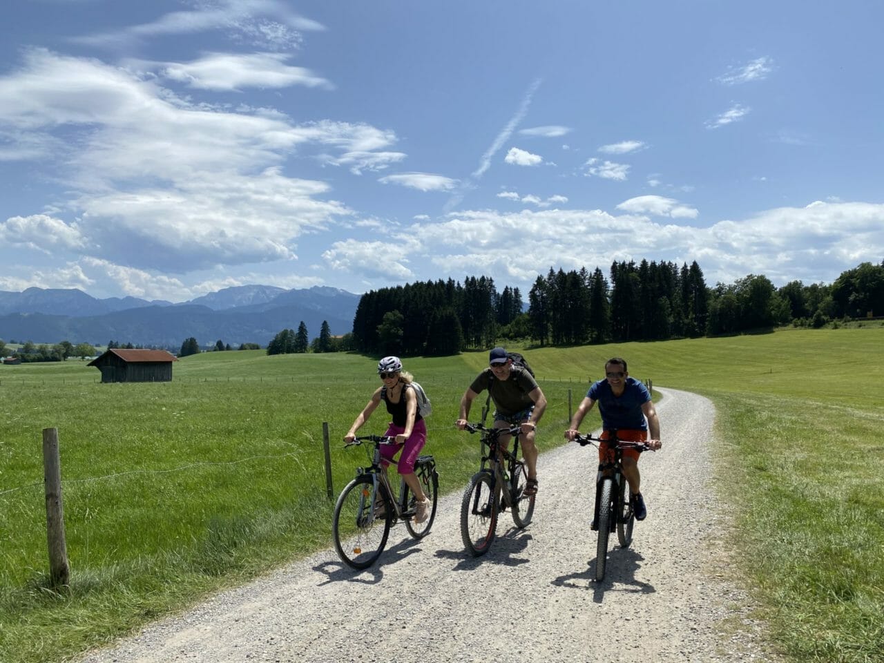 Radtour um den Forggensee bei Füssen Drei Radfahrer vor einer grünen Wiese und Bäumen