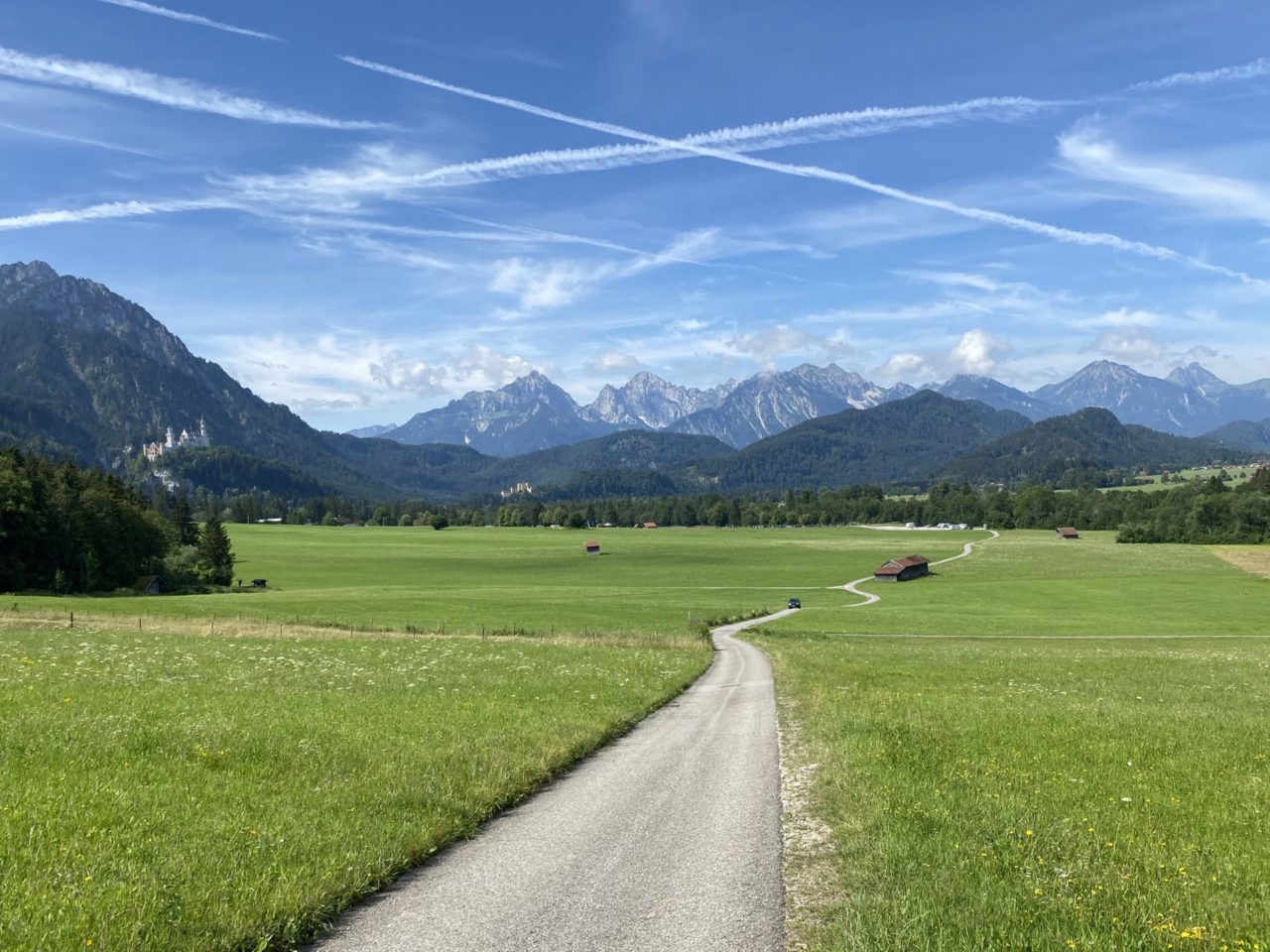 Ein Blick auf die Berge mit Schloss Neuschwanstein Ein Wanderweg mit Blick ins Grün und Berge